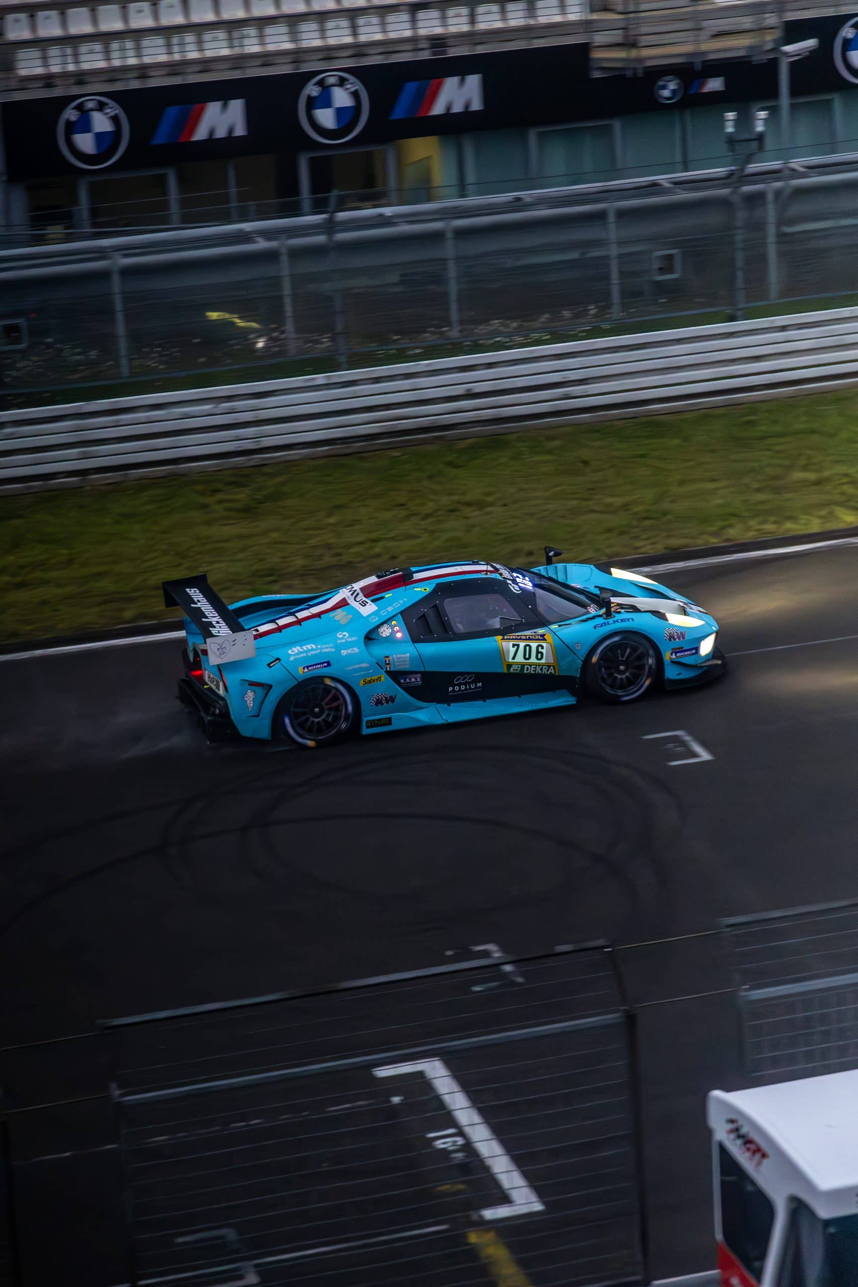 An aqua race car seen from above along the circuit edge.