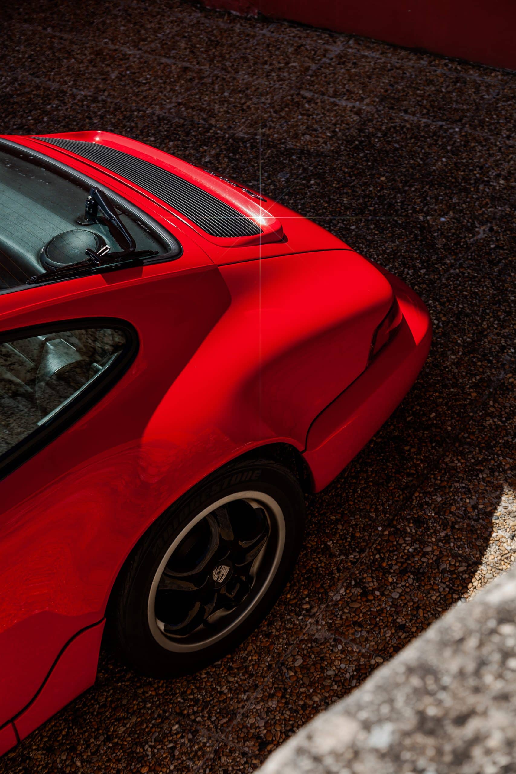 A close crop highlighting the side body line of a red sports car.