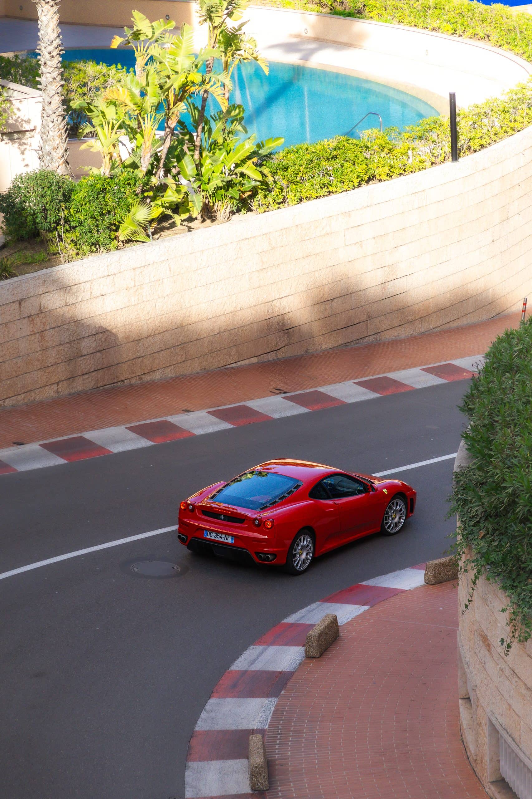 A red coupe photographed from above on a curving downhill road.