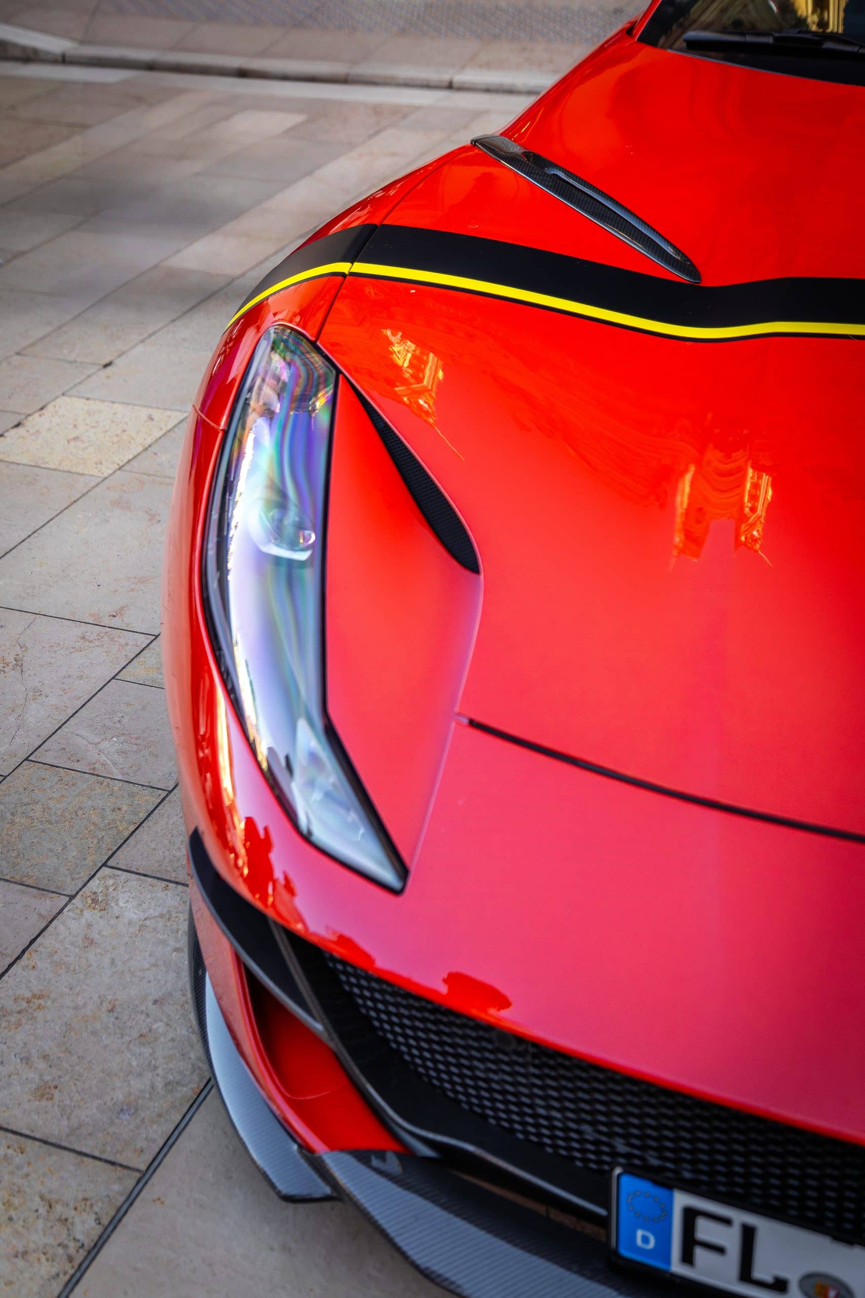 A close front-end study of a red supercar with strong surface reflections and contrast.