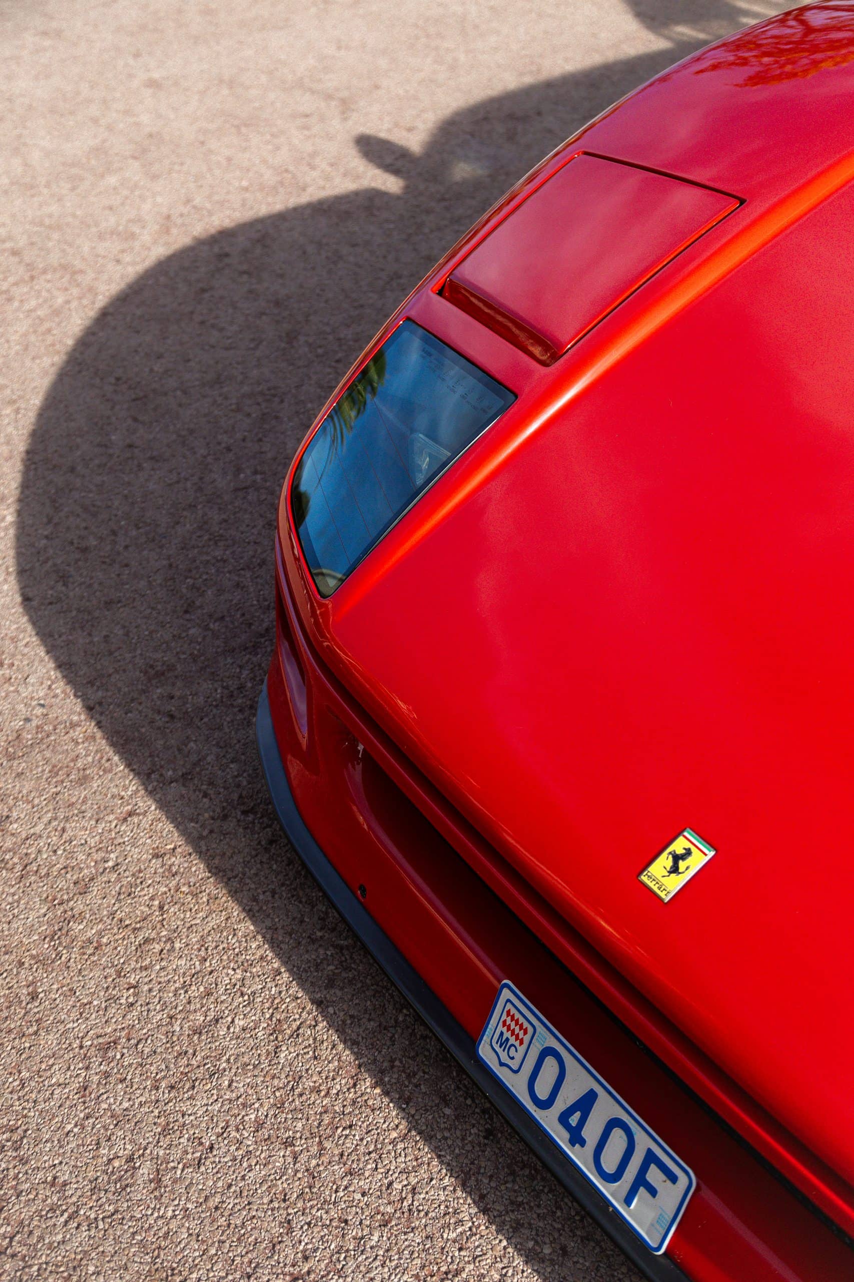 A close detail of a red hood and badge under strong daylight.