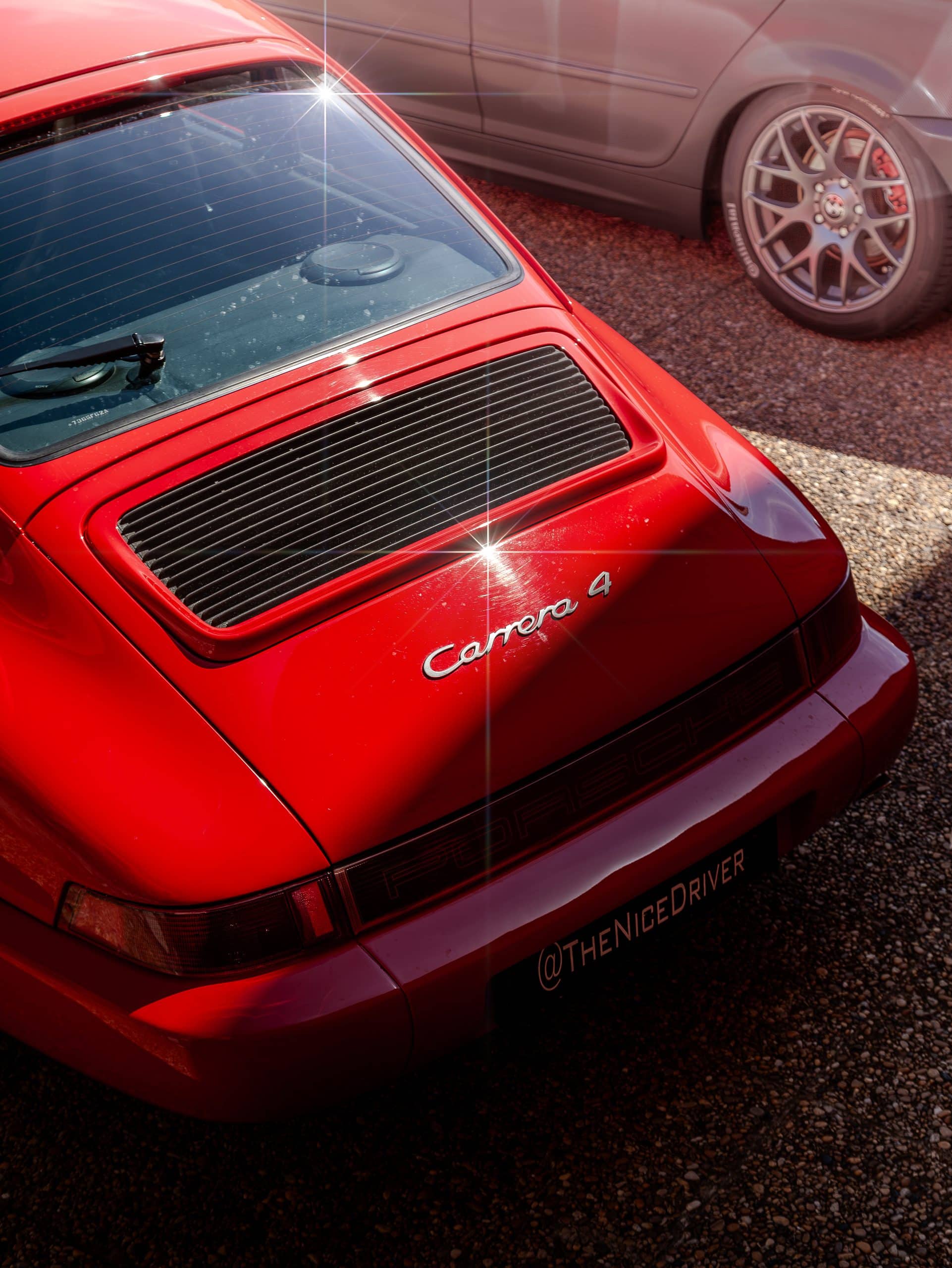 A close rear three-quarter study of a red sports car with grille details.