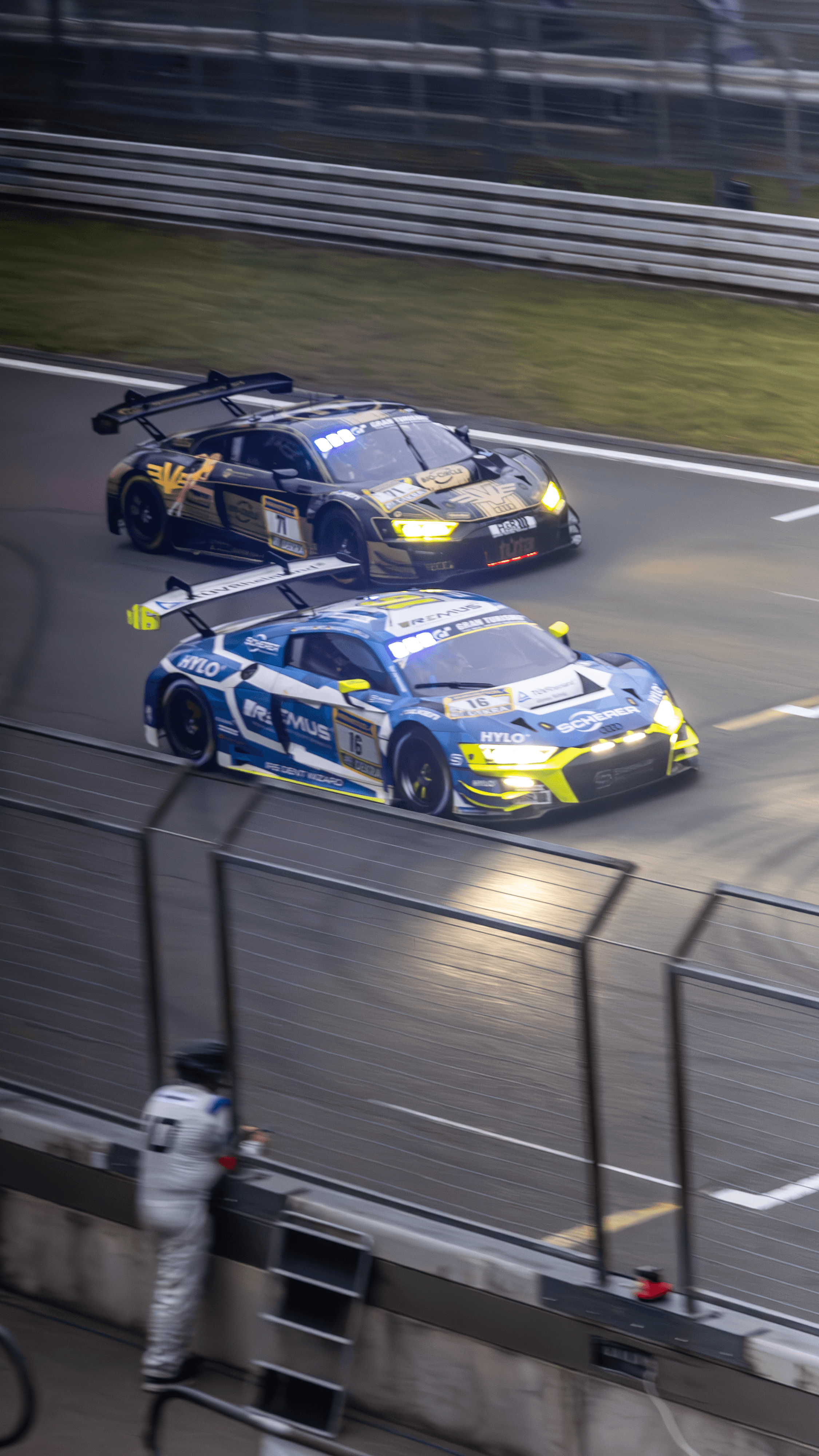 Two race cars captured at night under circuit lighting.