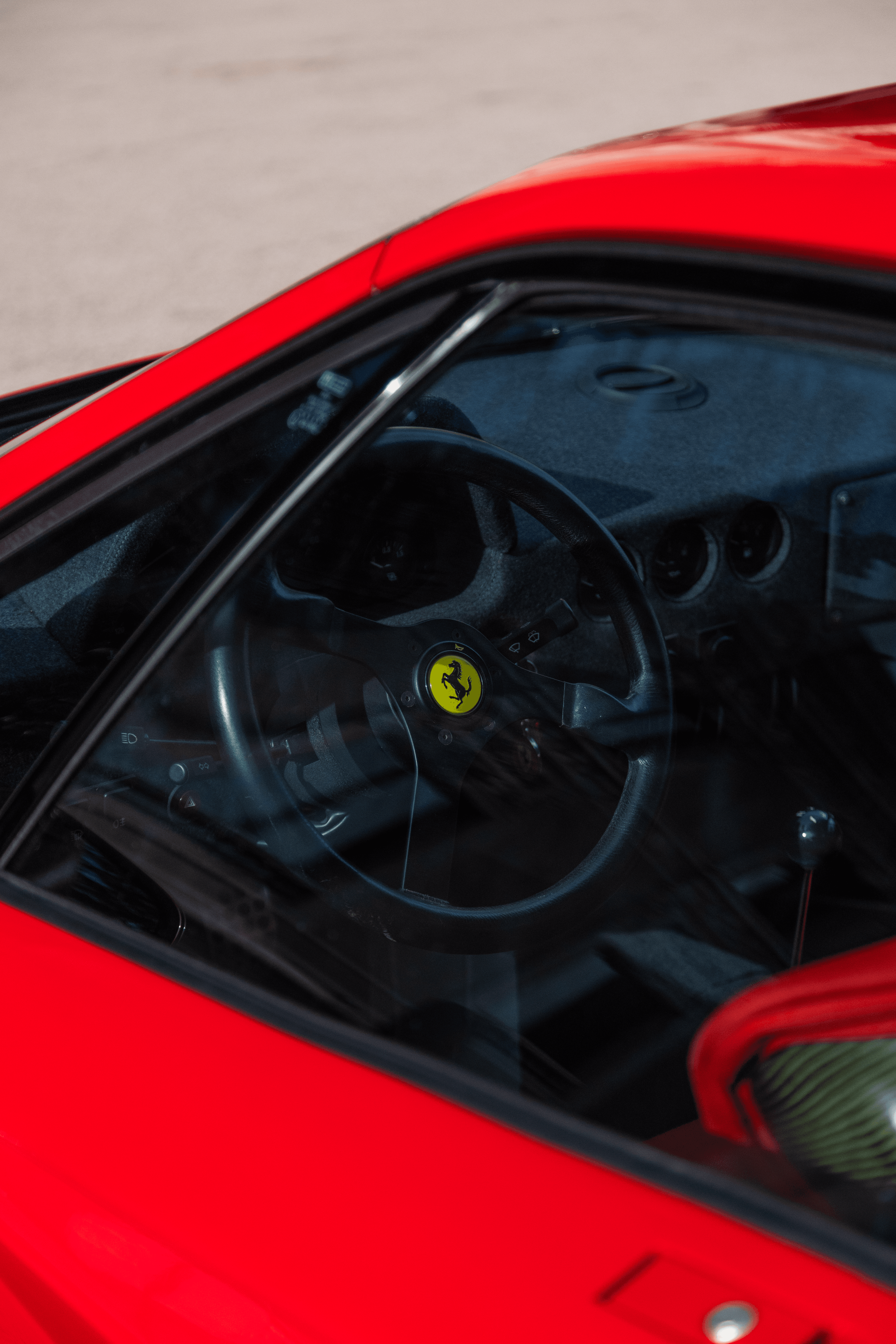 A close crop through the side glass of a red sports car cabin.