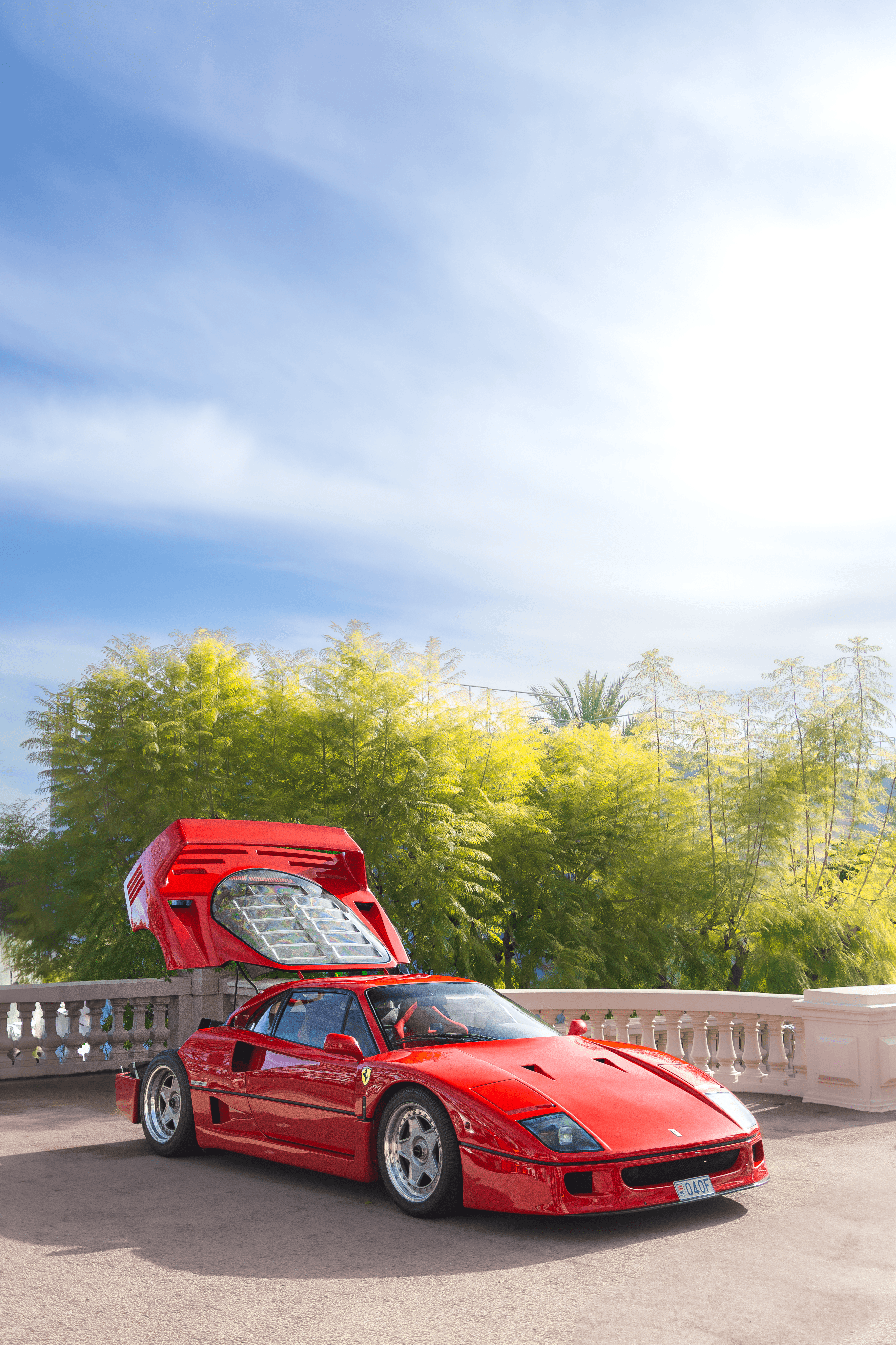 A red coupe photographed front-on in warm light with a hillside backdrop.