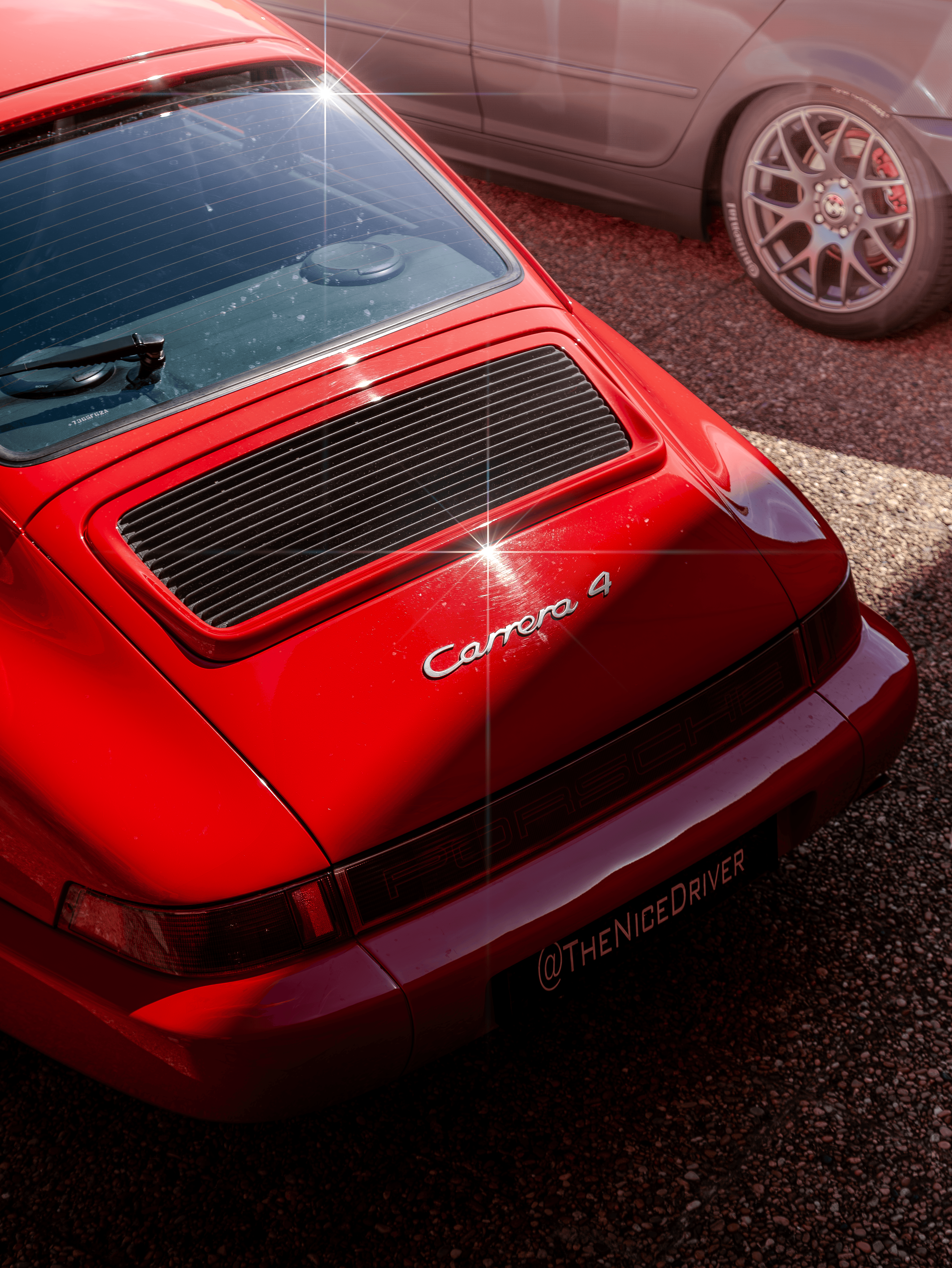 A close rear three-quarter study of a red sports car with grille details.
