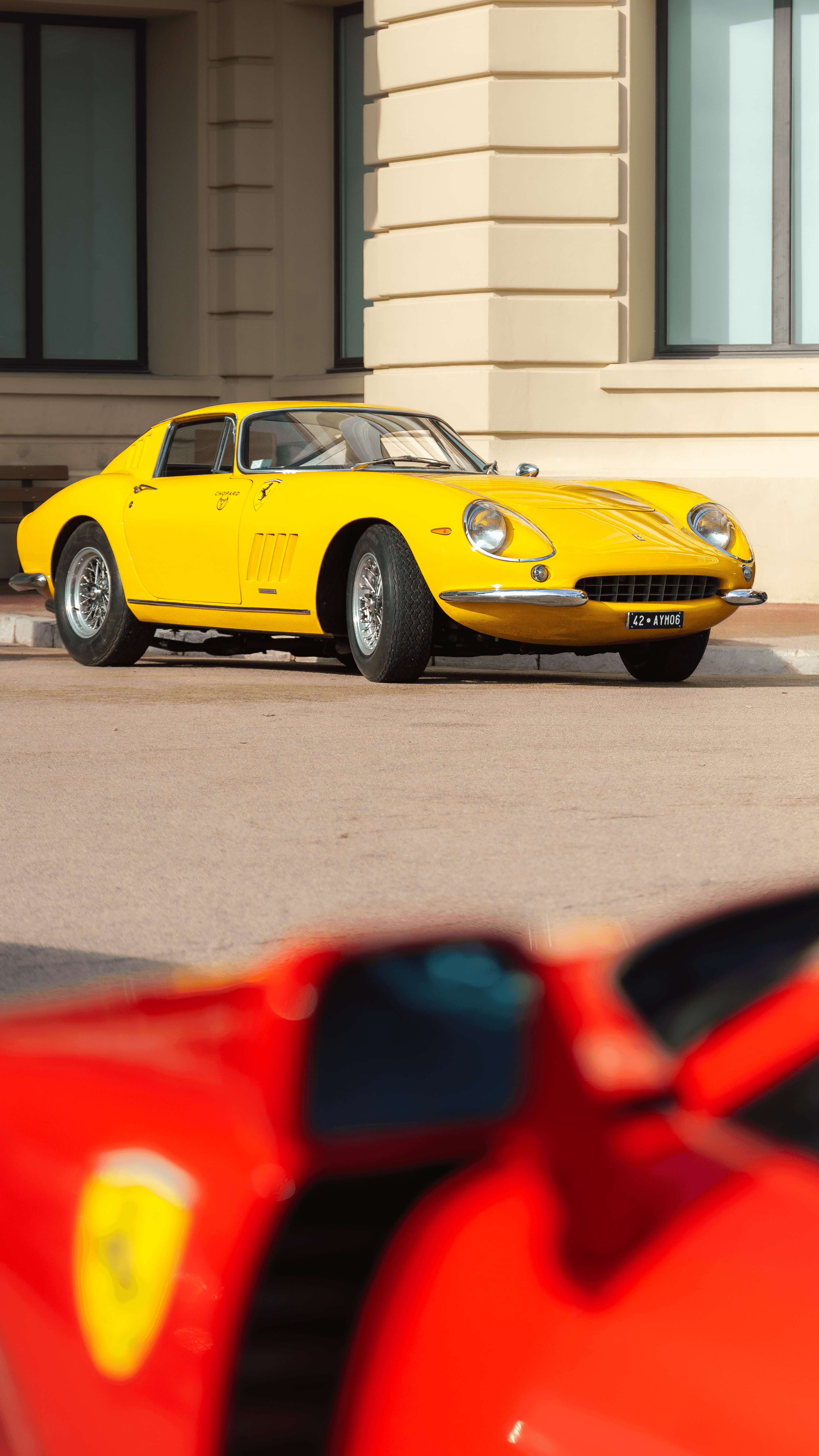 A yellow coupe placed within a composed courtyard setting.