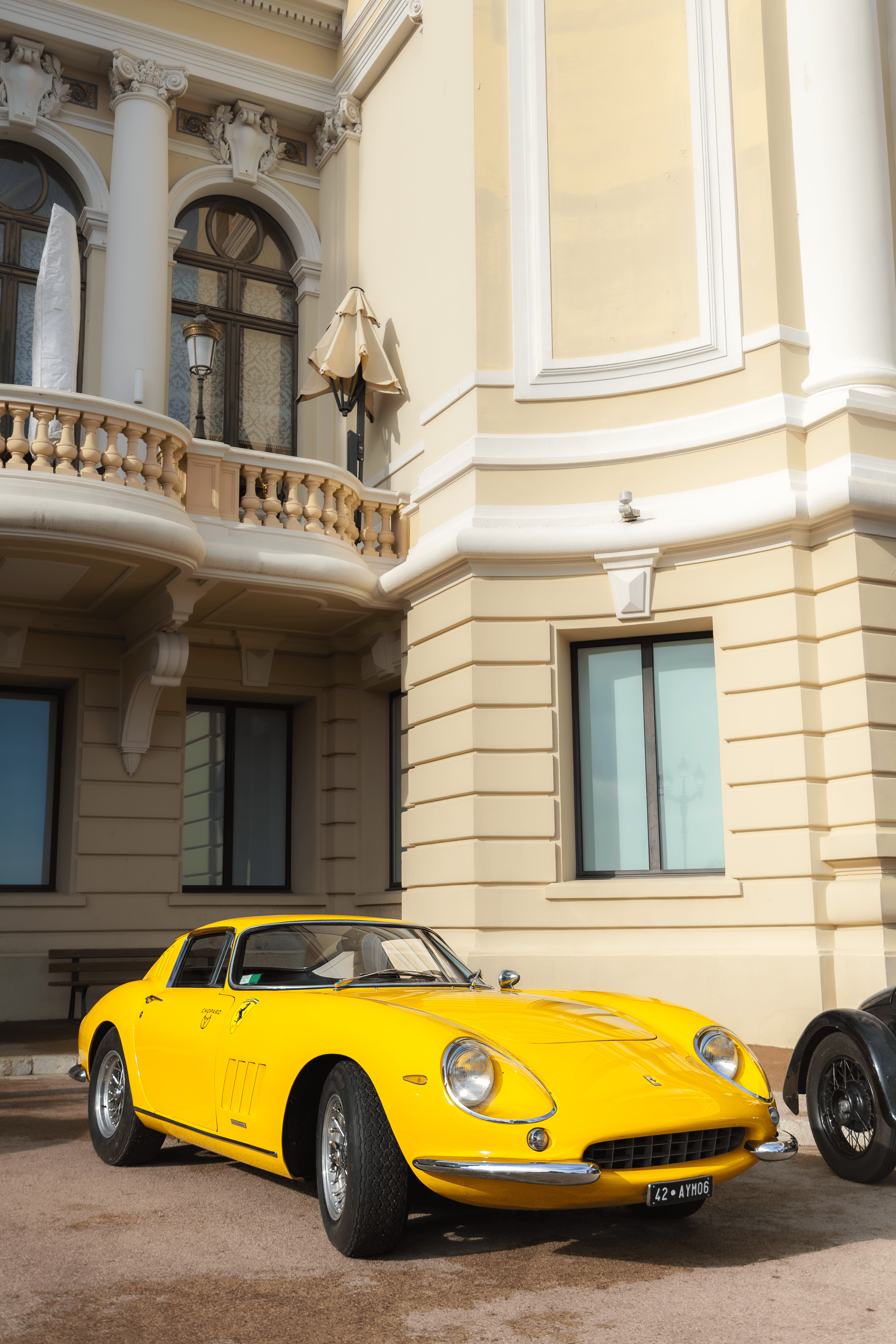 A yellow coupe framed against a historic facade and architectural columns.