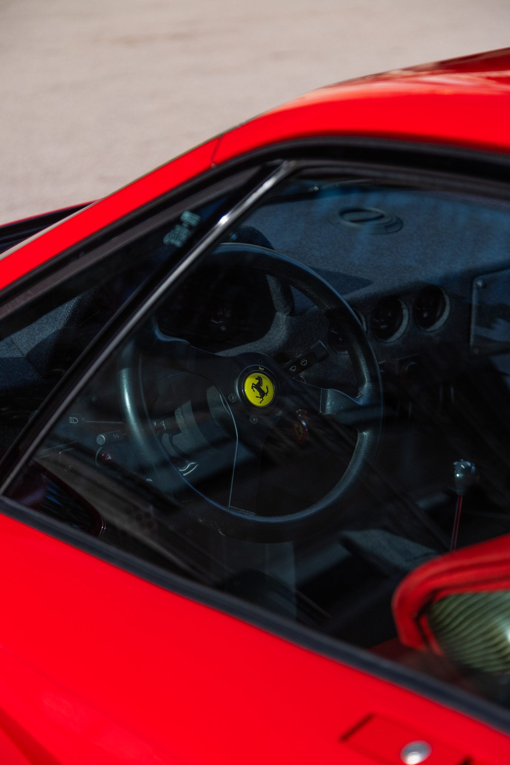 Through the side window: the cabin and steering wheel of a red supercar.