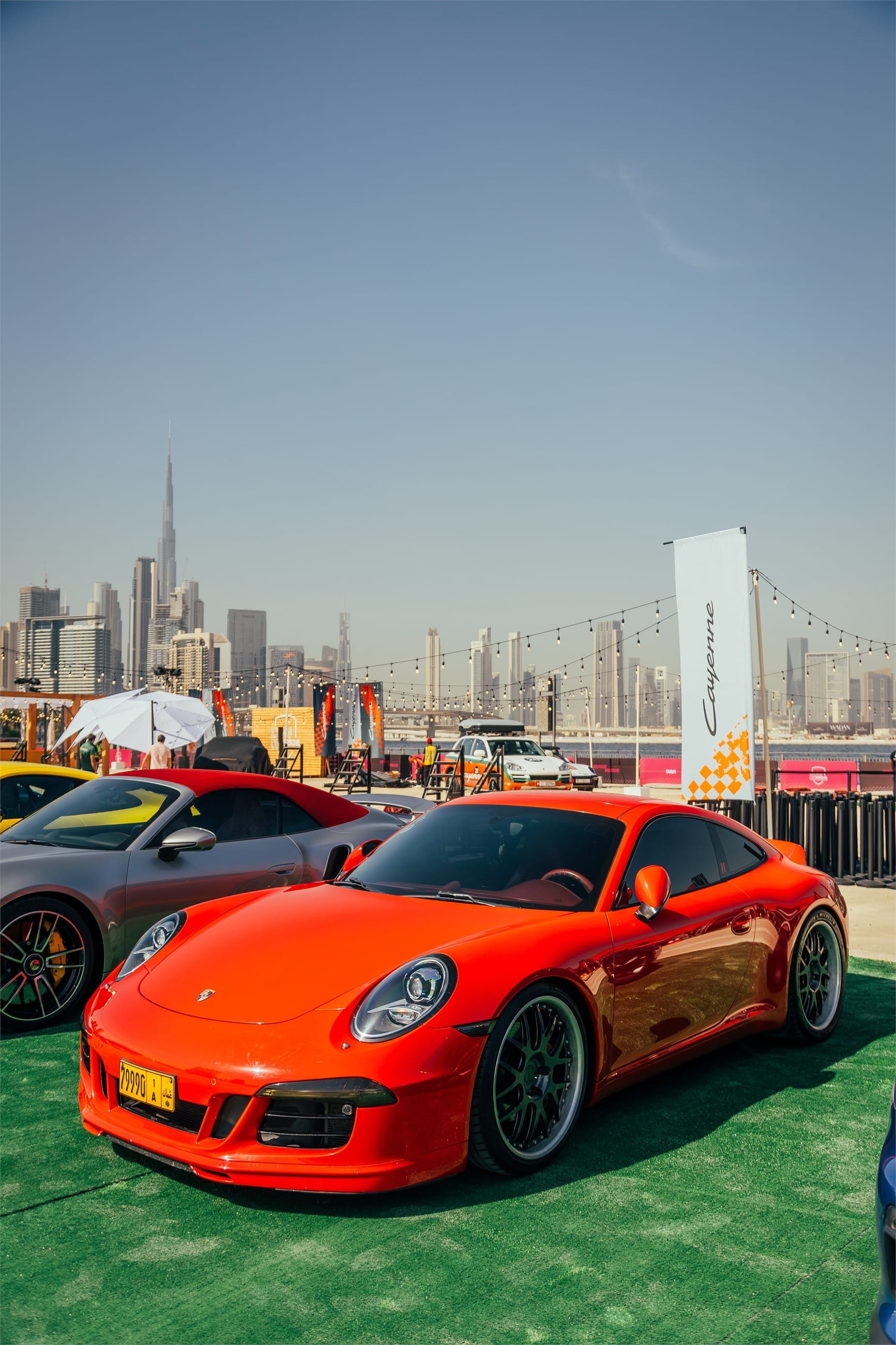 Red Porsche 911 on green turf, the downtown skyline behind.
