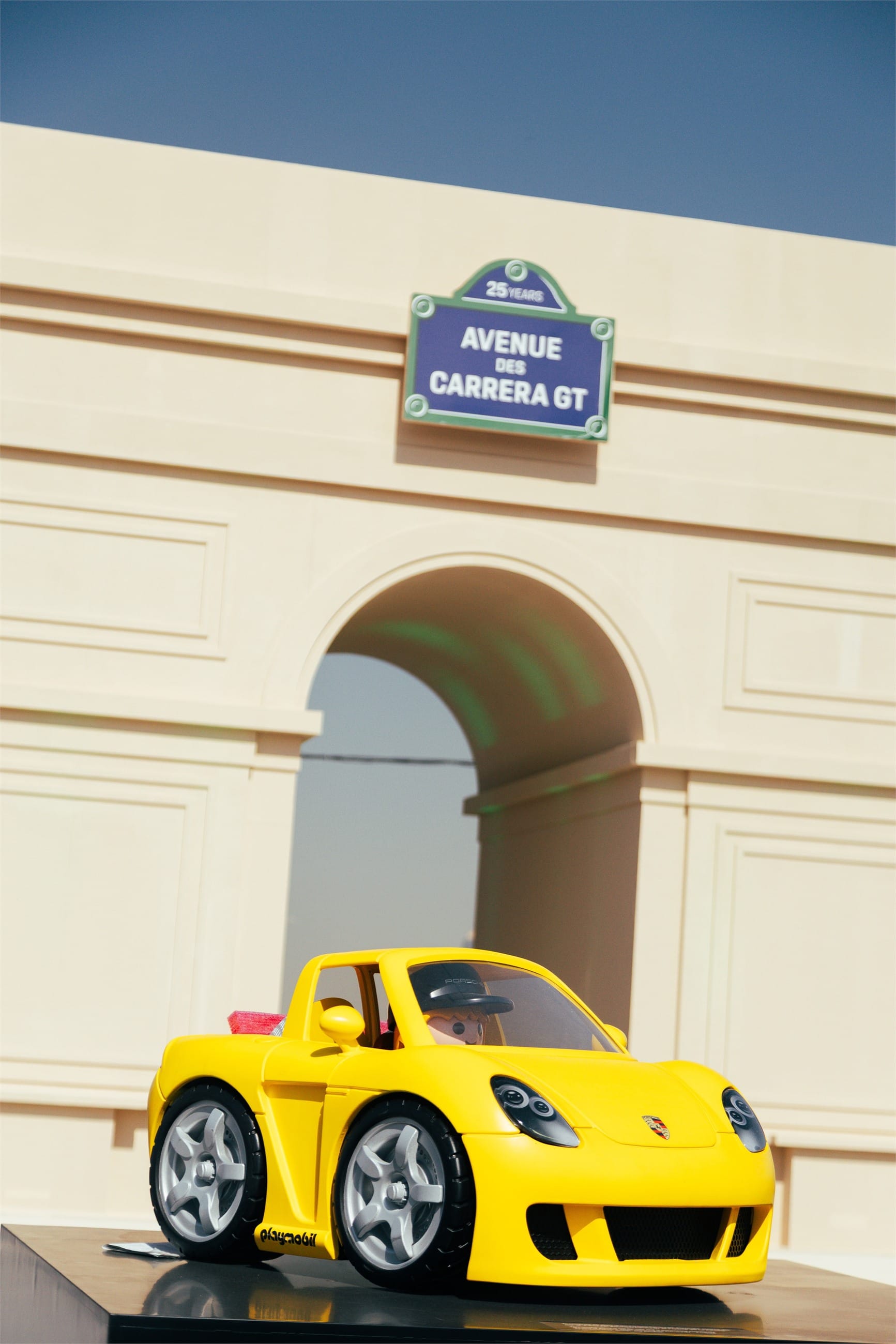 A small yellow children's car under a sign reading Avenue des Carrera GT.