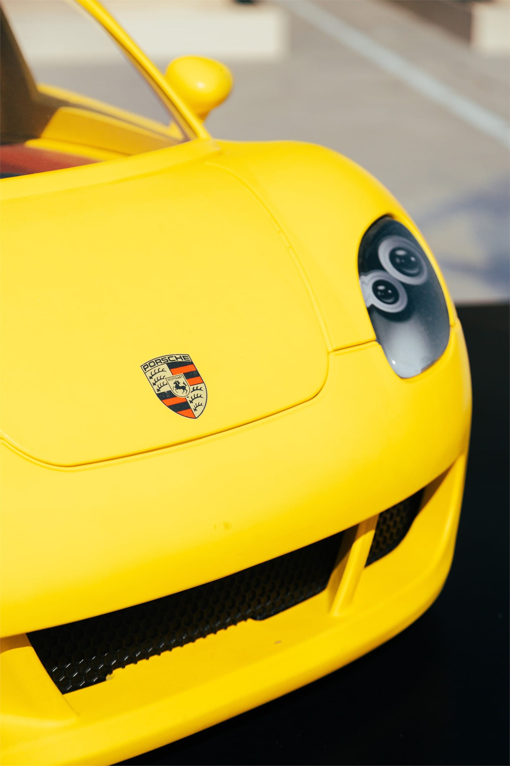 Close detail of a yellow Carrera GT's headlight and crest.
