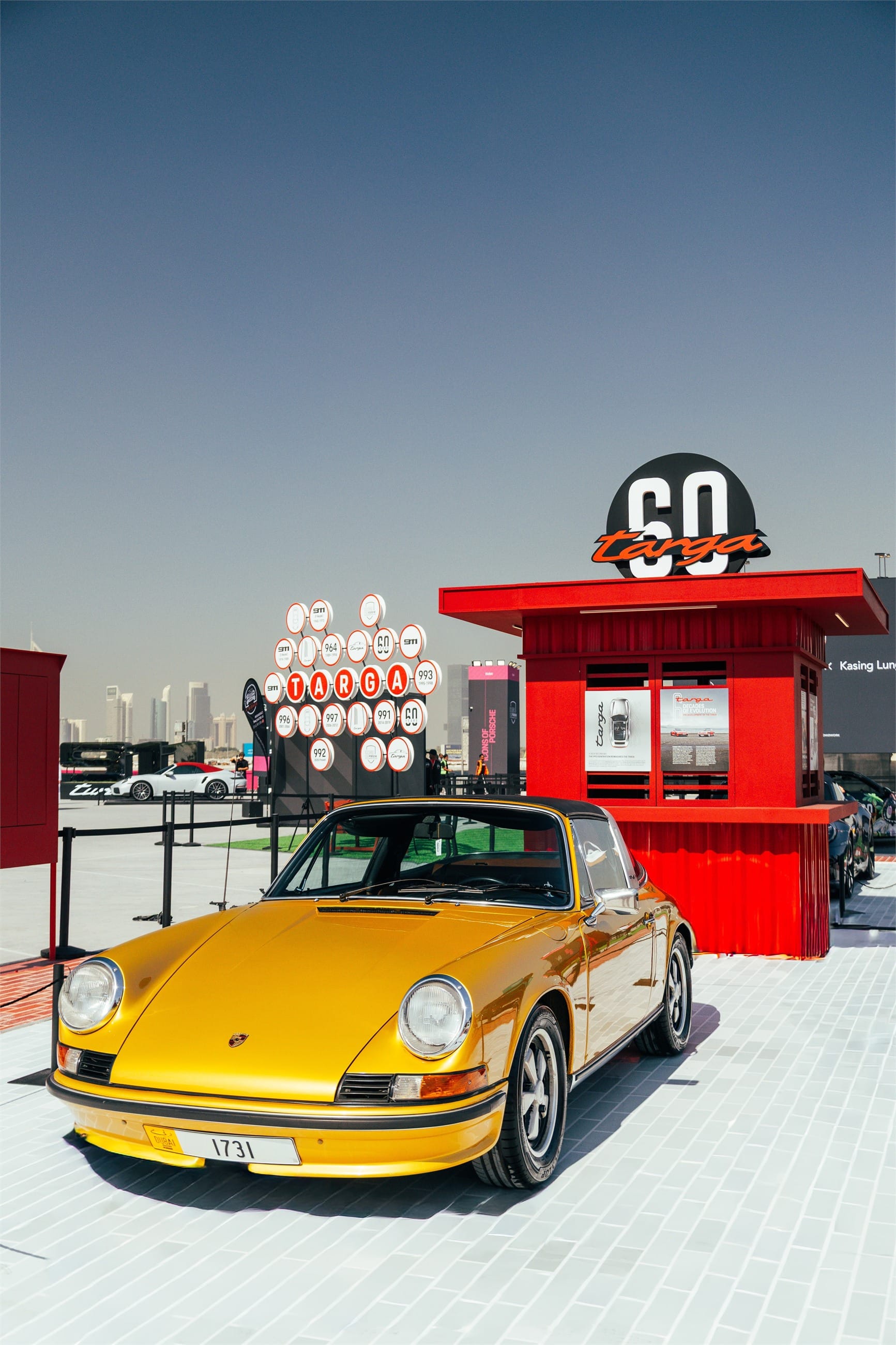 Gold classic 911 in front of a red kiosk.