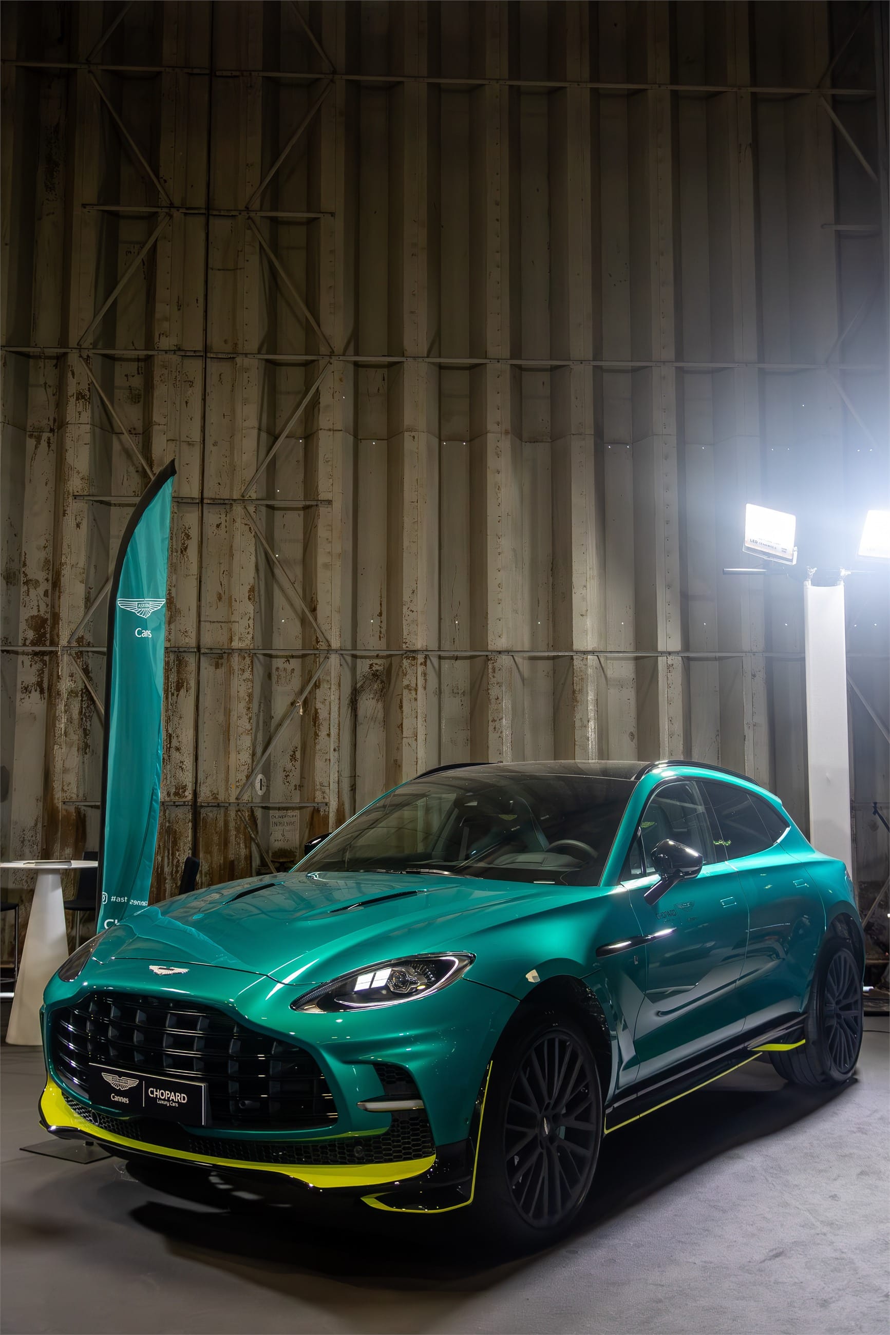 Green Aston Martin SUV under bright studio lights.