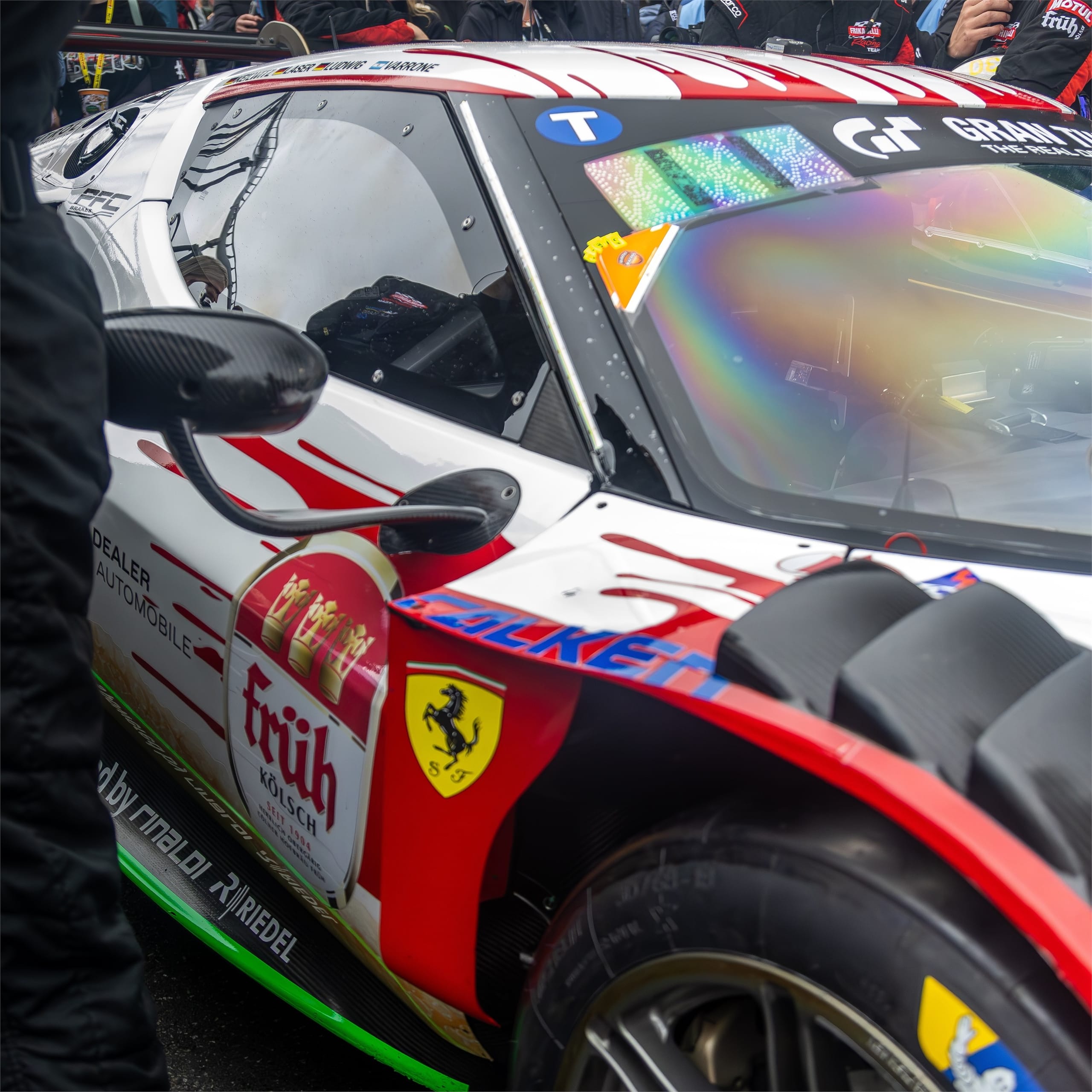 Detail of a white and red racing car's livery and front wheel arch.