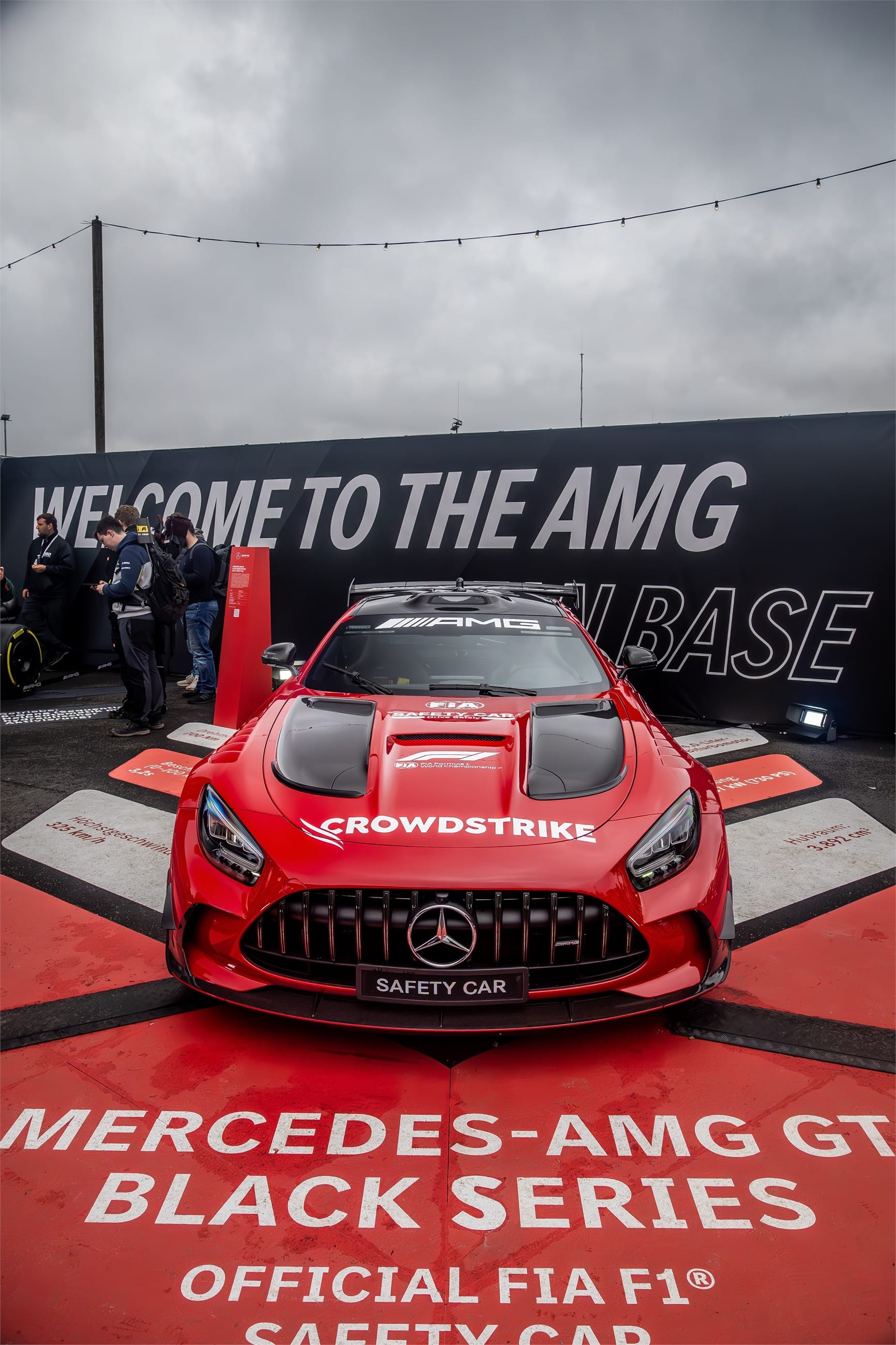 Red safety car displayed on a stand at the fan zone.