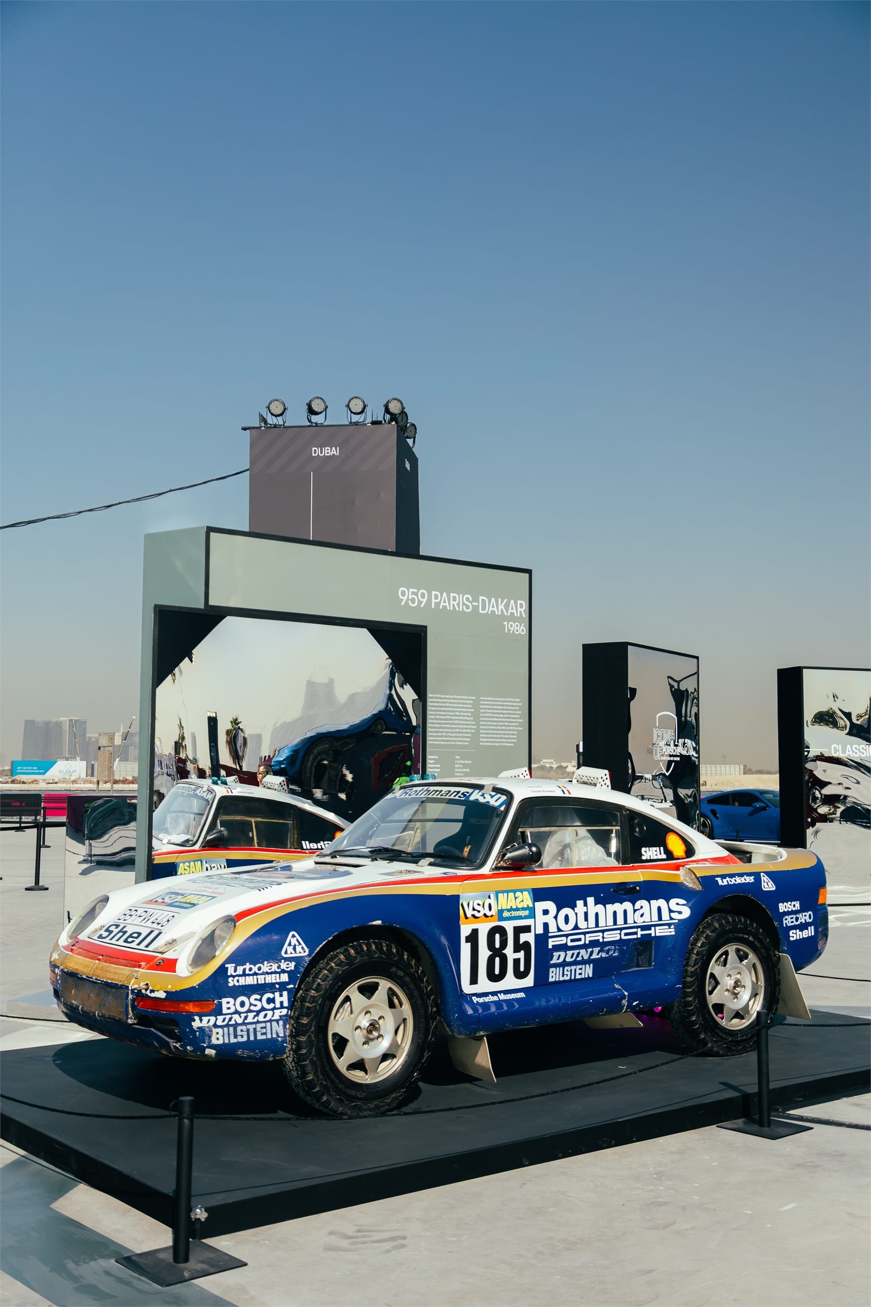Rally Porsche in blue and white livery on a display stand.