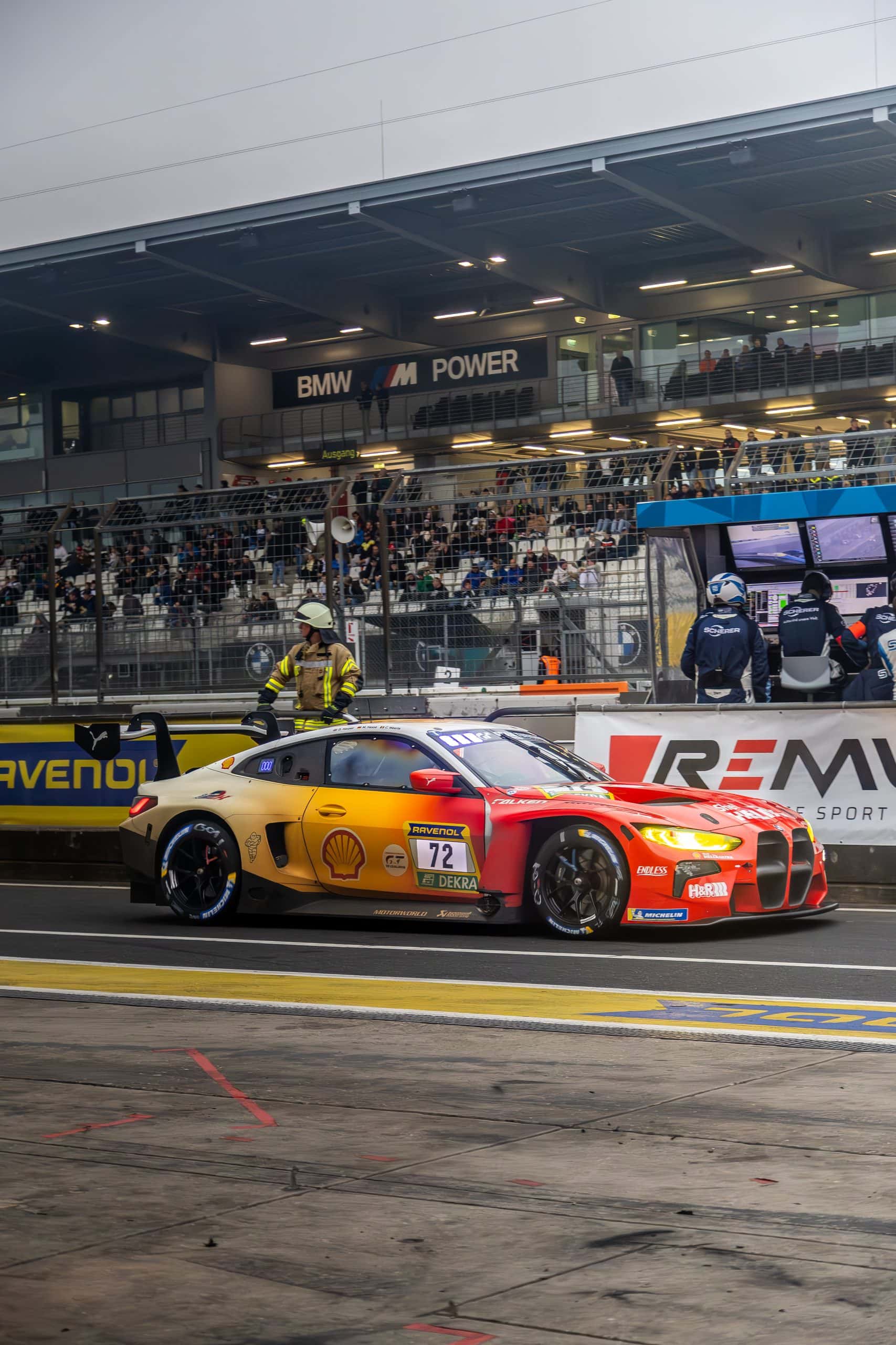 A race car passing at speed with warm light and grandstand atmosphere.